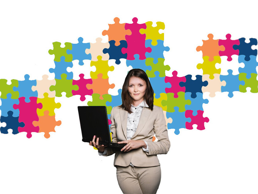 Kvinna med dator står framför pusselbitar
